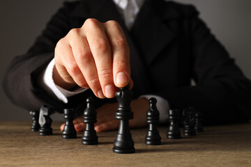 A man in a black suit with chess on the table