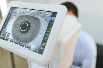 Handsome man getting an eye exam at ophthalmology clinic. Checking retina of a male eye
