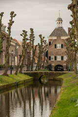 binnenhaven road leading to town hall Stadhuis van Nieuwpoort in historic fortified town on Old Dutch Waterline on cloudy stormy day. old building and bridge reflection in city canal