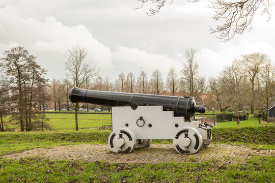 antique cannon on edge of historic Holland fortified town Nieuwpoort. Star shaped walled city near river Lek part of Old Dutch Waterline defense from flood water and enemies safeguarding inhabitants	