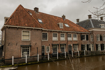 street in traditional Dutch rural town old centre Linschoten, Netherlands. Residential houses on next to canal water during daytime in bad weather cloudy skies