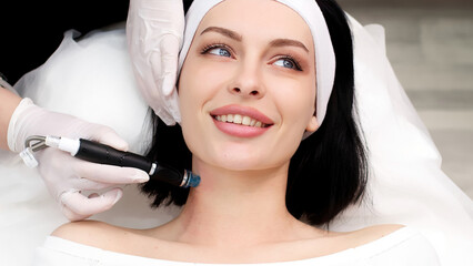 A professional dermatologist in medical gloves performs a hydropeeling procedure on a young woman...