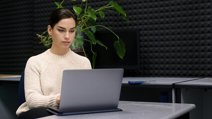 Young business professional woman working using laptop, sitting at desk in home office. Business woman working on a new project after completing a work plan.