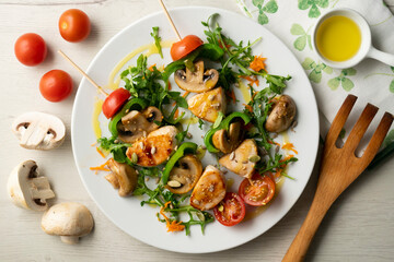 Organic chicken skewers with mushrooms and salad.