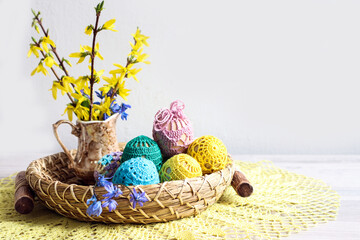 Easter composition with a bouquet of flowers and painted eggs on a decorative tray on a light background
