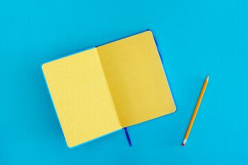 Open yellow notepad on a blue background, top view.