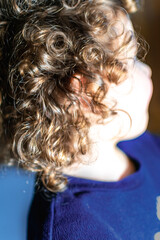 Obraz premium Natural curly hair, little girl with light brown curls and golden reflections