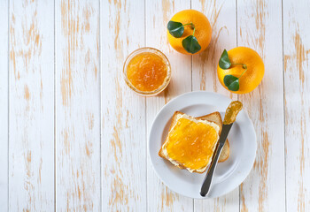 Toasts of bread with orange jam and fresh fruits  on white wooden table. Top view.