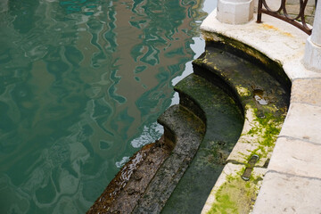 Stone Stairs covered with algae along a canal during low tide in Venice in Italy. Green Canal...
