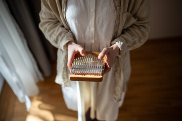 Closeup of ethnic kalimba in woman hands, above view. Learning to play traditional acoustic African...