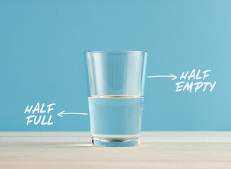 Optimism and Pessimism concept. Water glass with the words half full and half empty.