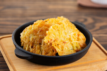 Potato pancakes, draniki, Latkes or Levivot in a cast iron frying pan on a wooden table. Hanukkah, Passover food.
