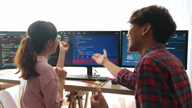 Slow motion back end software developer engineer for computer programming working together on debugging writing computing code, solving complex algorithms display on monitor in office. Burgeoning