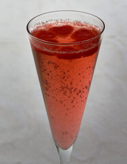 A champagne glass looks to hold pink champagne with heart ice cubes.