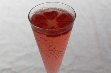Red, heart shaped ice cubes float on top of pink champagne