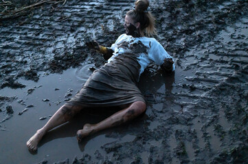 A happy authentic woman stuck in a mud puddle in a field