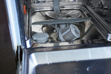 Dishwasher filter in the bottom of the dishwasher. The concept of appliance repair, service and maintenance.