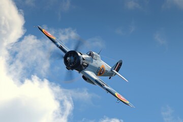 Gloster Gladiator aircraft in flight with cloud and blue sky background