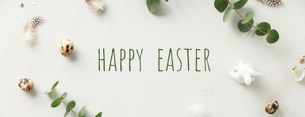 eucalyptus branches, eggs, feathers, ceramic bunny on light grey background