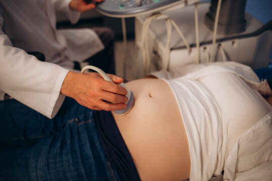 In the Hospital, Close-up Shot of the Doctor does Ultrasound Sonogram Procedure to a Pregnant Woman. Obstetrician Moving Transducer on the Belly of the Future Mother