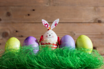 Fototapeta na wymiar Row of colorful Easter eggs and bunny rabbit decoration on wooden background, copy space