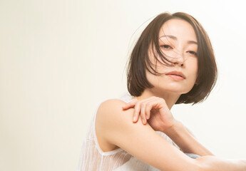 風で髪が靡いているクールな表情の美しいミドル女性/ヘアケア