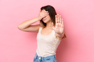 Young caucasian woman isolated on pink background making stop gesture and covering face