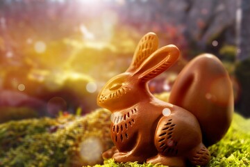 Small chocolate bunny sitting on green forest