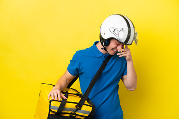 Young Brazilian man with thermal backpack isolated on yellow background laughing