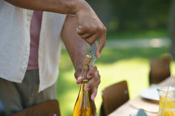 Close up of opening wine with wine opener at summer garden party.