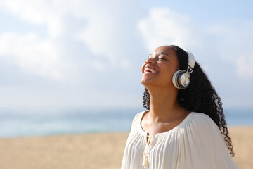 Happy black woman in white breathing with headphone