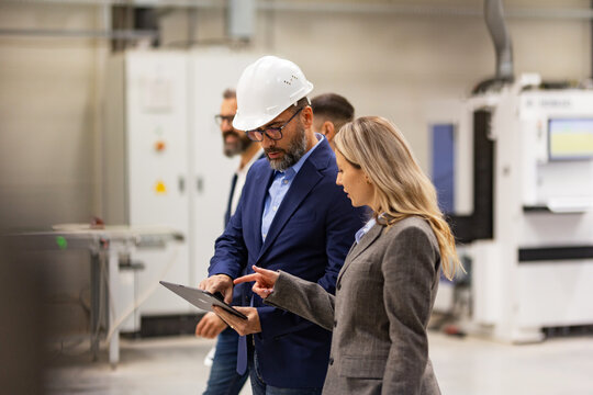 Engineer, foreman consulting with director in modern industrial factory, talking about new production project or investment. Team management in manufacturing facility.