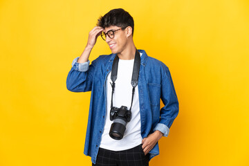 Young photographer man over isolated yellow background laughing