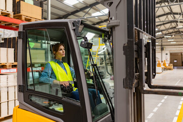 Female warehouse worker driving forklift. Warehouse worker preparing products for shipmennt, delivery, checking stock in warehouse.