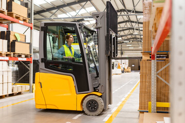 Female warehouse worker driving forklift. Warehouse worker preparing products for shipmennt, delivery, checking stock in warehouse. - obrazy, fototapety, plakaty