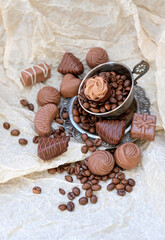 Fototapeta na wymiar Beautiful Praline Chocolate sweets. assorted chocolate candies, Cup and coffee beans on paper background. tasty milk fine chocolate.
