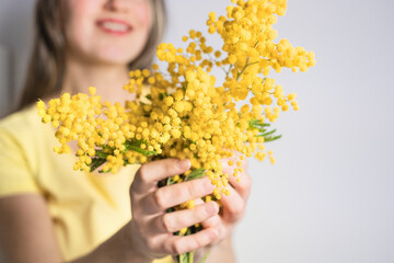 Beautiful young woman with mimosa flowers on white background