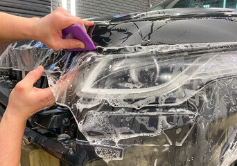 Car wrapping. A car wrapping specialist applies a polyurethane film to the car. Selective focus. PPF protective film against chips and scratches. Paint protection. 