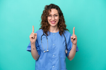 Young nurse caucasian woman isolated on blue background pointing up a great idea