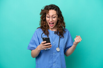 Young nurse caucasian woman isolated on blue background surprised and sending a message