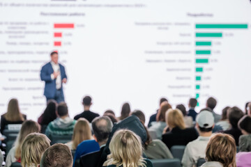 Corporate speaker presenting to an attentive audience in a conference room, with focus on data...