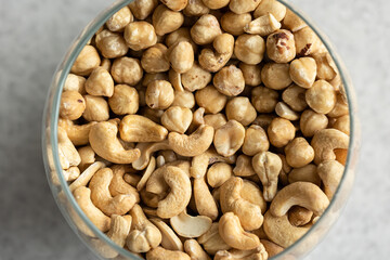 Mix of cashews and hazelnuts in a glass vase, close-up.