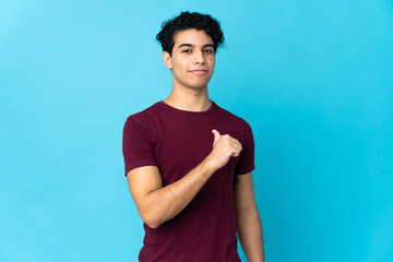 Young Venezuelan man isolated on blue background proud and self-satisfied