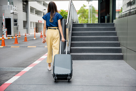 A businesswoman pulling her luggage down a flight of stairs with handrails, ensuring safety and convenience during her journey.
