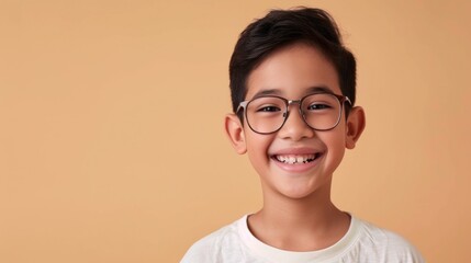Young boy with glasses smiling against a warm orange background.