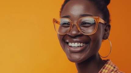 Smiling woman with glasses and hoop earrings wearing a plaid shirt against an orange background.