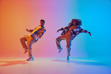 Dynamic photo of two dancers, man and woman move synchronously in hip-hop style dance against...