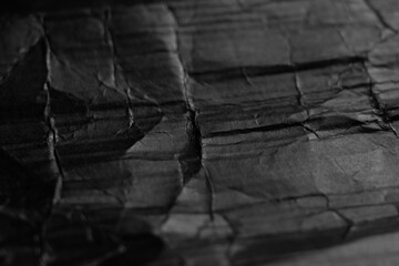 Crumpled black paper with wrinkles and folds. Dark abstract background