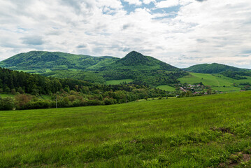 Fototapeta na wymiar Huge fresh green meadow, small village and mostly forest covered hills above - beautiful Starzovske vrchy mountains in Slovakia