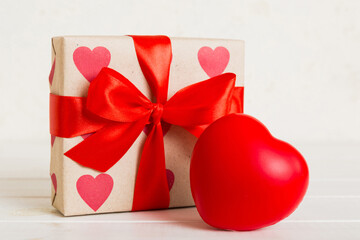 gift box with red bow and red heart on colored background. Perspective view. Flat lay